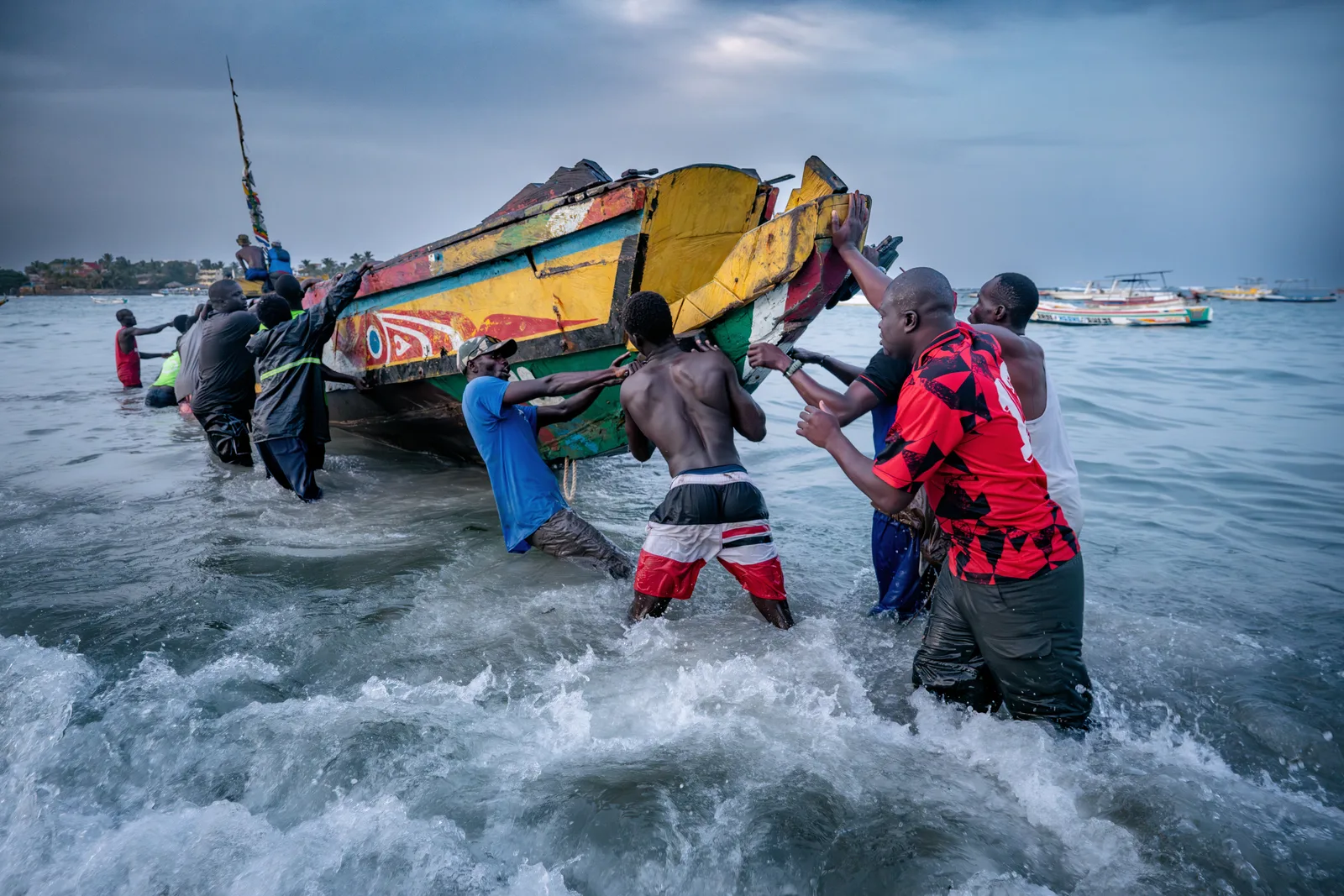 Eine Gruppe von Männern schiebt ein Boot, das zuvor von Migranten benutzt wurde, zurück ins Meer